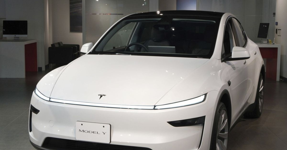 O mașină albă Tesla, Model Y, expusă la un salon auto din Japonia