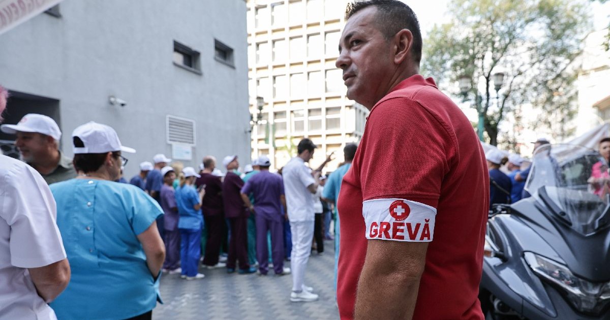 Un angajat din sanatate cu banderola de greva la mana sta in fata spitalului Floreasca