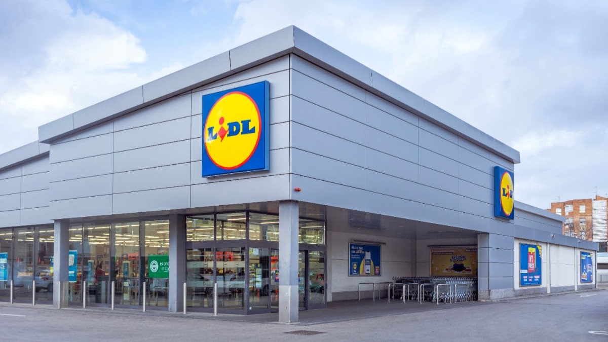 Intrarea într-un magazin Lidl, parcarea este goală și în interiorul supermarketului lumina este aprinsă