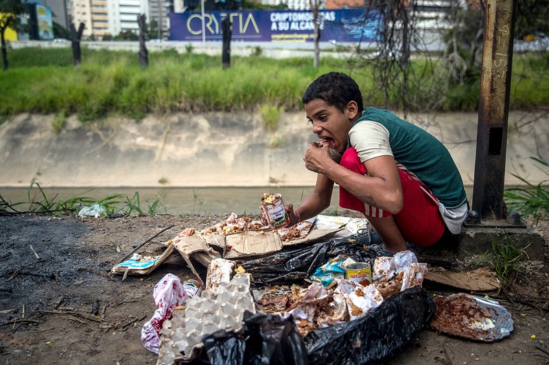 Jesus, 16 ani, mănancă dintr-o pungă de gunoi care i-a fost dăruită într-o brutărie, în cartierul "Las Mercedes", în Caracas, Venezuela, 10 noiembrie 2018 Foto:EPA-EFE / MIGUEL GUTIERREZ