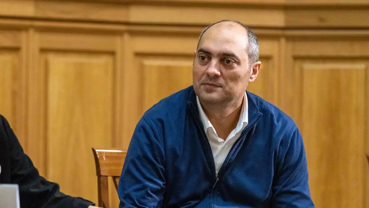 Gelu Duminică îmbrăcat într-un pulover albastru și cămașă albă