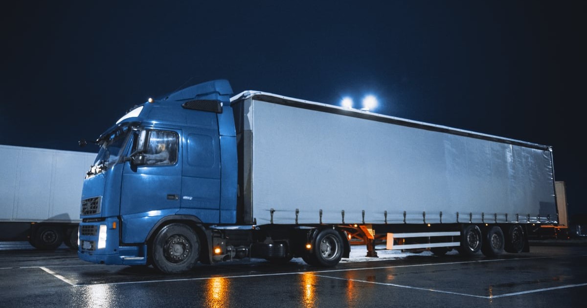 Un TIR cu cabină albastră într-o parcare, noaptea