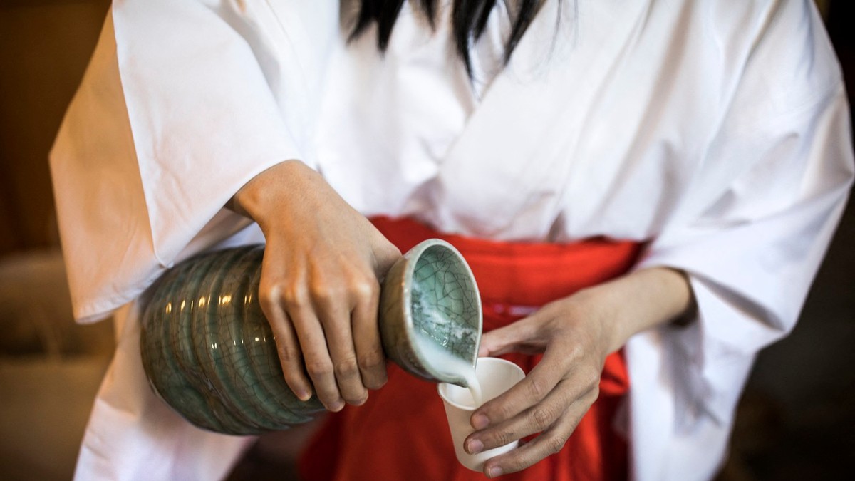 O femeie toarnă Doburoku, o vch băutură japoneză, într-un pahar
