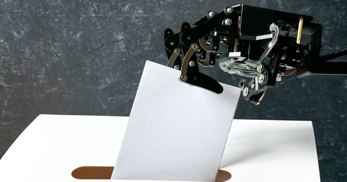 O mână robotizată introduce un buletin de vot de hârtie într-o urnă albă.