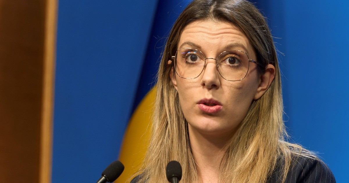 Diana Buzoianu, îmbrăcată în sacou negru, în timp ce vorbește la microfon.