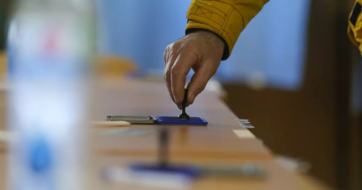 În imagine este ilustrată o persoană care ține o ștampilă de vot