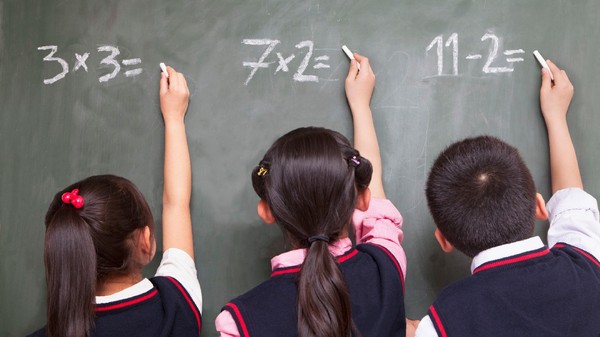 Trei elevi care rezolvă exerciții de matematică la tablă