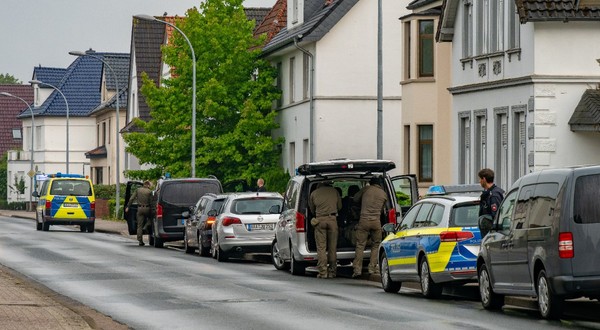 Mașini de poliție parcate în fața unei case din Germania, în timpul unei interventii