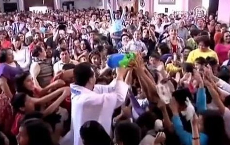 La asta nu te-ai fi gândit! Un preot foloseşte un pistol de jucărie pentru a răspândi apa sfinţită! | VIDEO