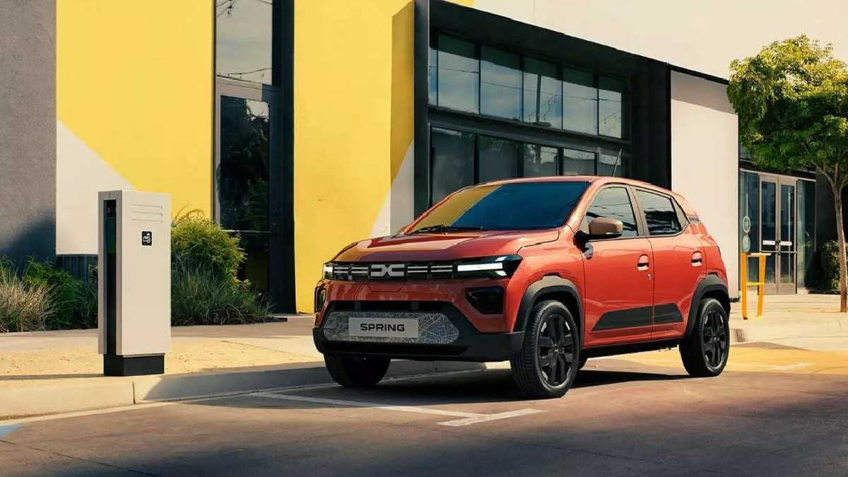 Mașină Dacia Spring în fața unei clădiri, lângă o stație de încărcat