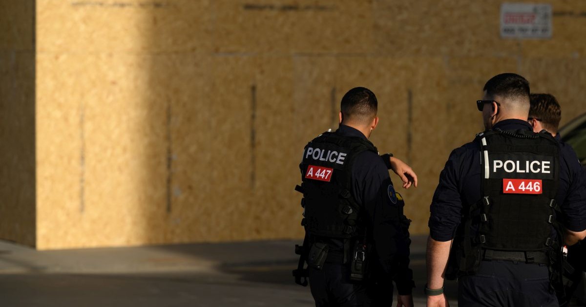 Polițiști patrulează lângă o clădire protejată cu panouri din lemn, montate în anticiparea protestelor legate de summitul G7 care urmează să aibă loc în apropiere, la Evian, pe 13 iunie 2026, la Geneva, în Elveția