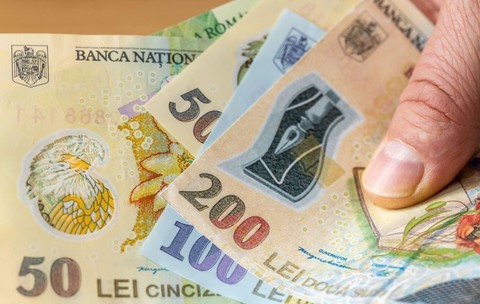 Mai multe hârtii de bani românești, de 50 de lei, 100 de lei și 200 de lei, pe care le ține în mână un bărbat