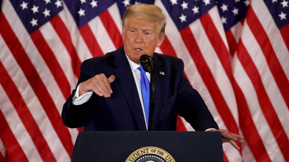 donald trump in timpul unui discurs, in spatele sau steagul americii