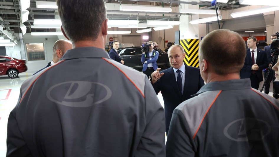 Președintele rus Vladimir Putin discutând cu angajați purtând uniforme marca Lada, în interiorul unei fabrici auto.   