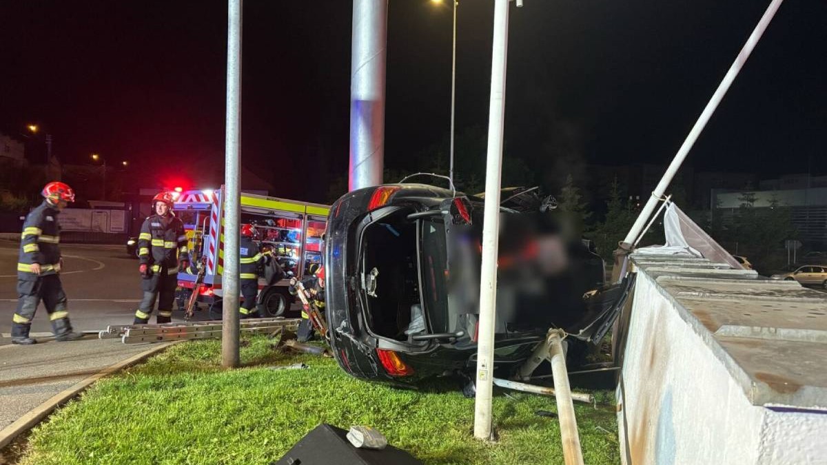 Imagine cu mașina răsturnată și cu doi salvatori la fața locului