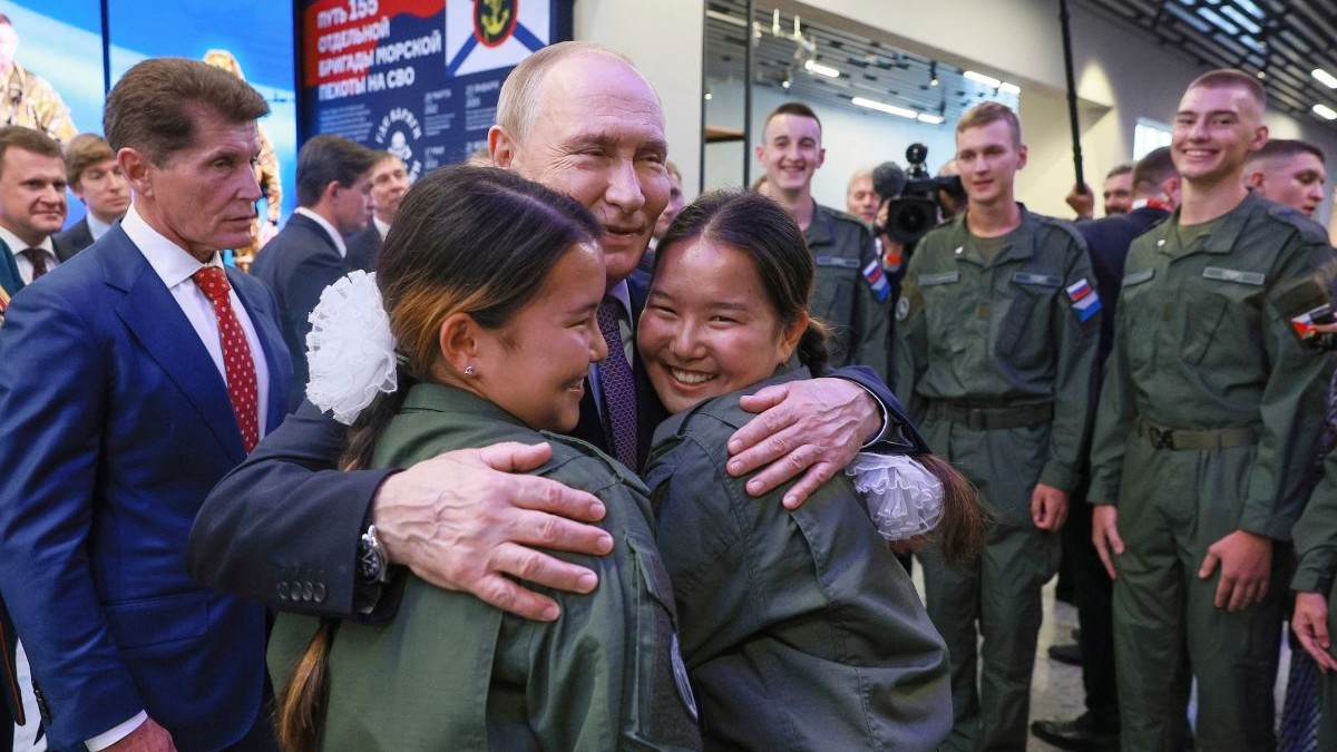Vladimir Putin îmbrățișează râzînd două tinere îmbrăcate în uniformă militară