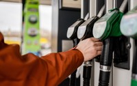 Bărbat care apucă o pompă de combustibil la o benzinărie 