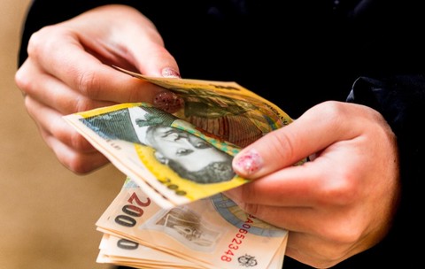 O tânără care numără mai multe bancnote de 200 de lei 