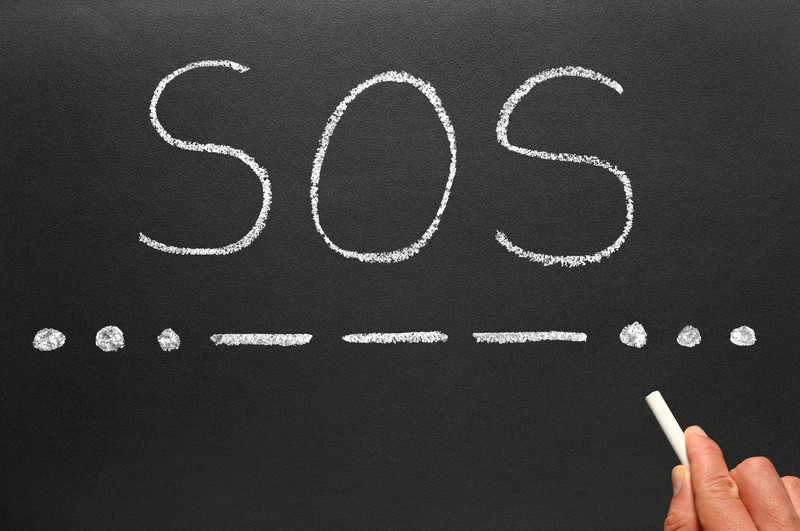 SOS the international Morse Code distress signal written on a blackboard.