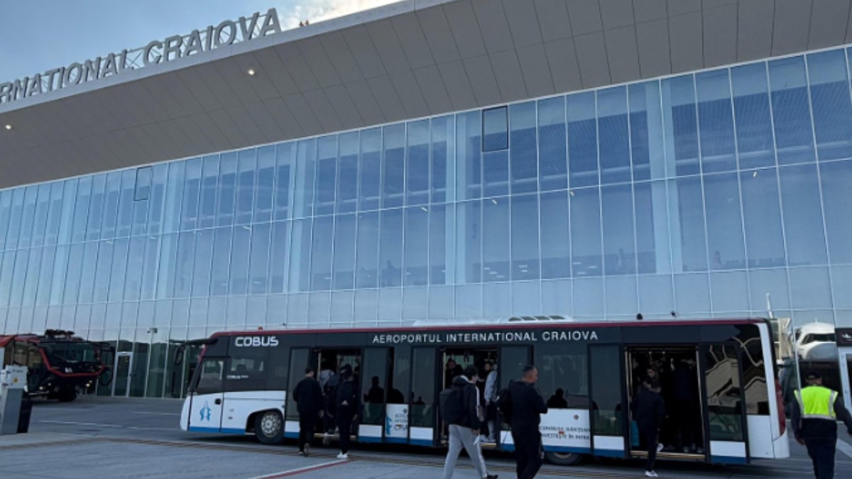 Oameni care urcă într-un autobuz, la aeroportul Craiova