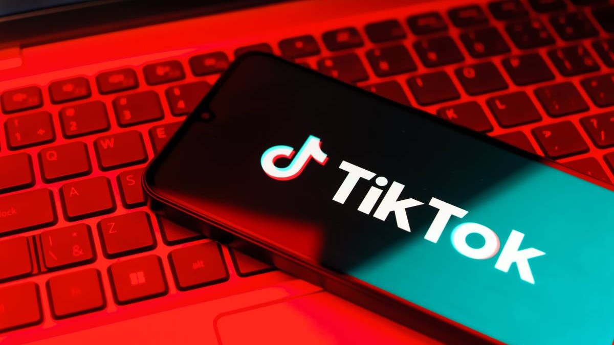 Aplicația TikTok instalată pe un telefon așezat pe tastatura unui laptop.