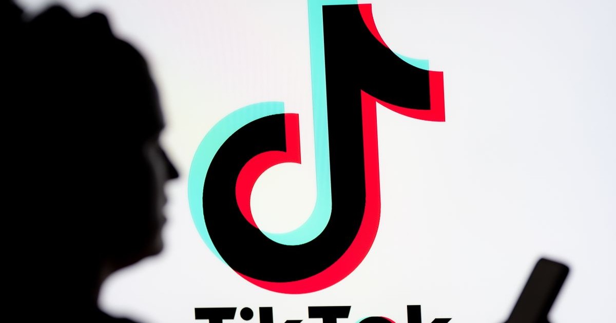 O femeie se uitâ pe un smartphone cu o siglă TikTok afișată în fundal