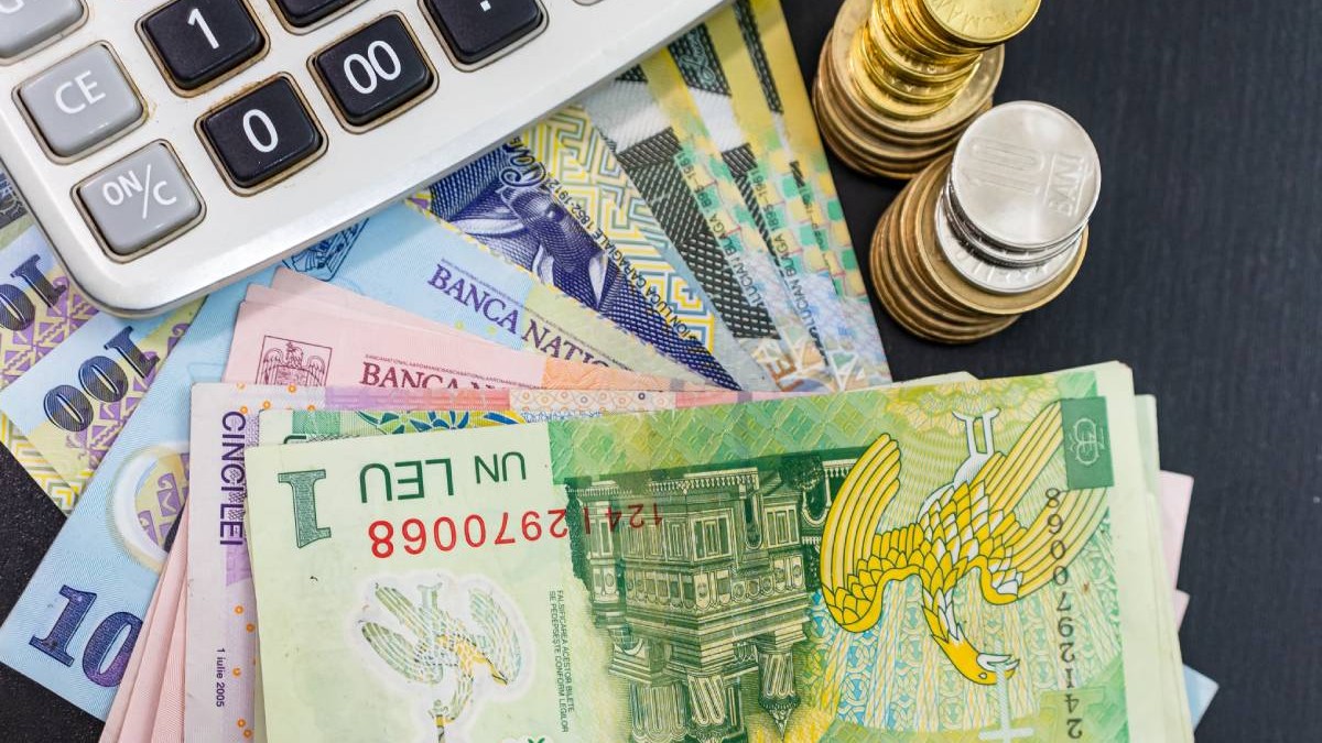 Mai multe bancnote românești de câte un leu, 10 lei și 100 de lei care stau pe masă