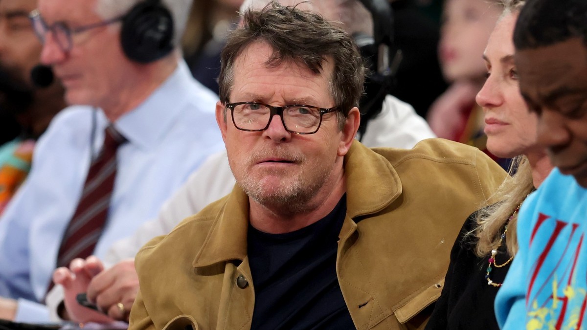 Michael J. Fox în tricou negru și jachetă galbenă în timp ce se uită în față
