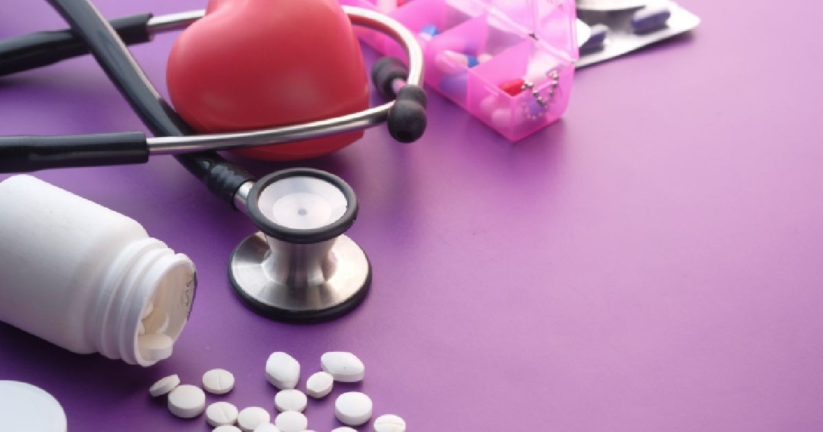 O inima si un stetoscop pe o masa mov si un flacon rasturnat cu medicamente . Bolnavi de inima