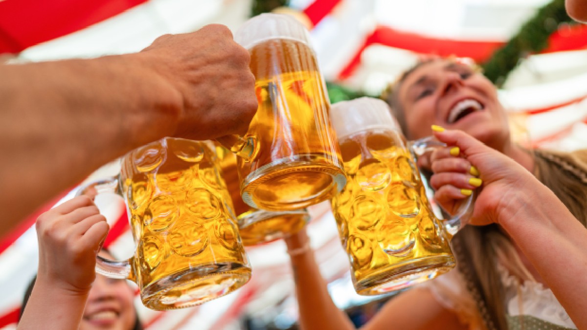 Grup de prieteni fericiți care toastează cu căni mari de bere într-un cadru festiv Oktoberfest
