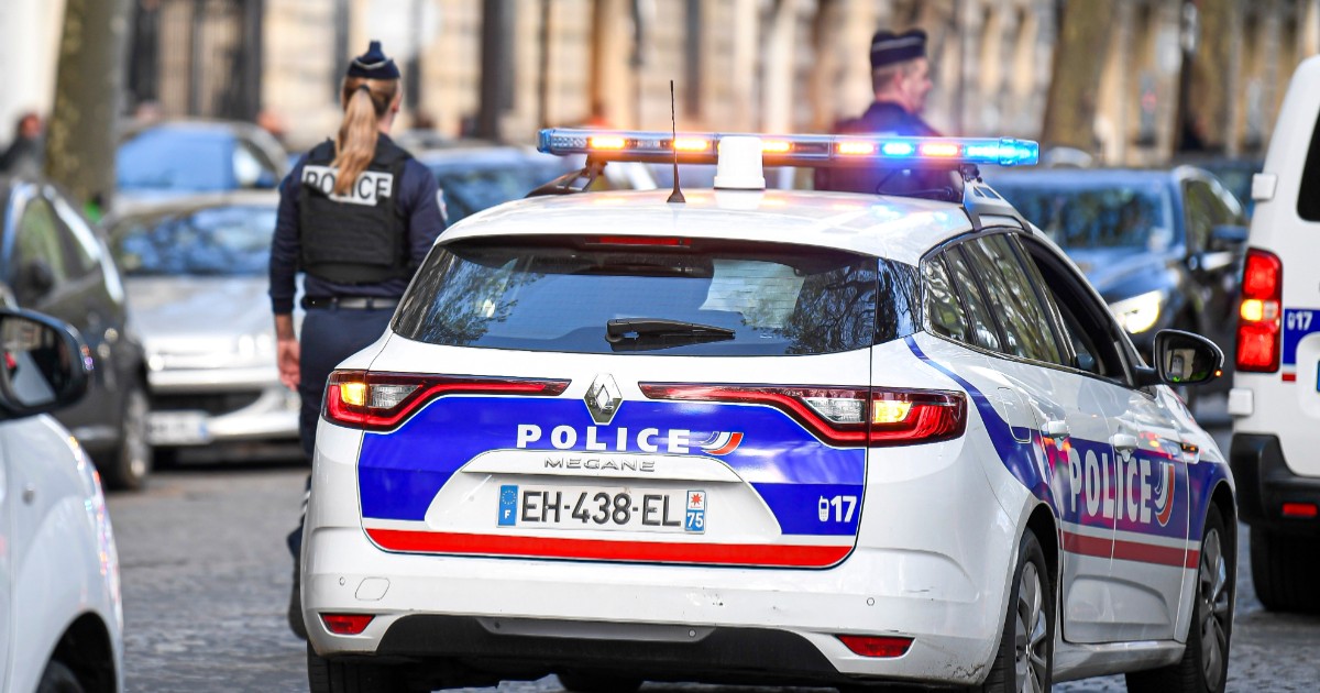 O polițistă lângă o mașină de poliție parcată pe șosea în Franța