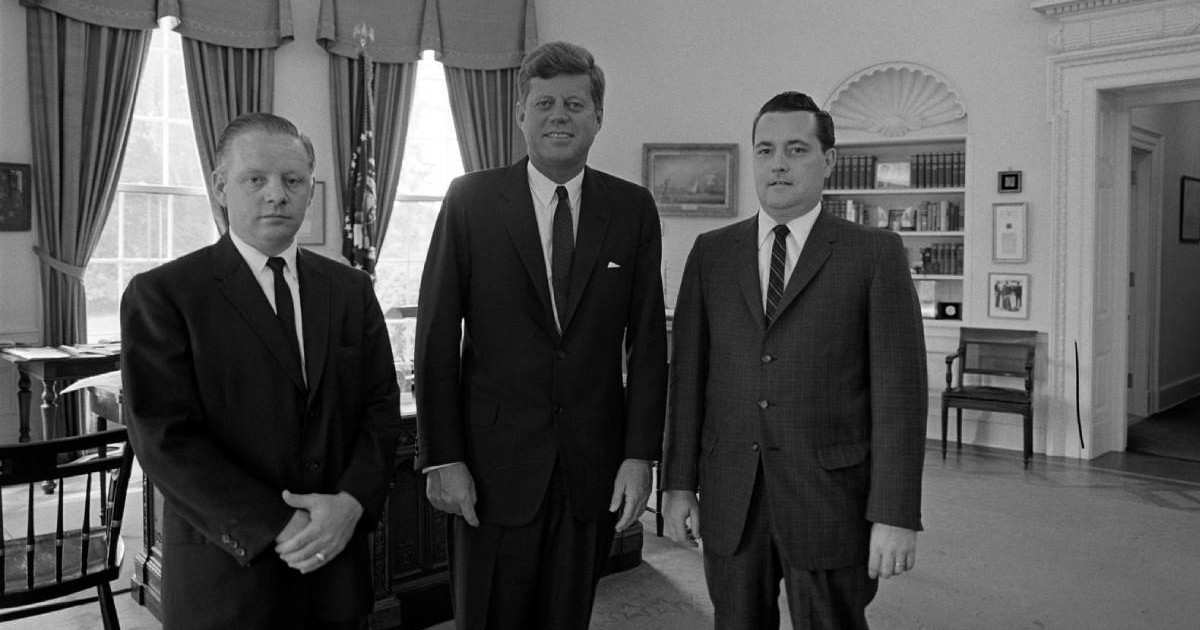 fotografie alb negru cu j.f kennedy alaturi de alti doi barbati. toti trei sunt imbracati la costum