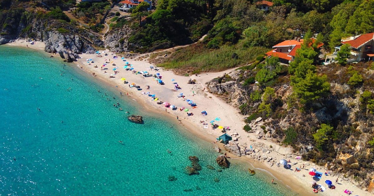 Plajă Grecia, marea albastra, umbrele și turisti intinsi la soare