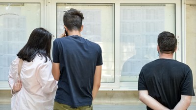 Imagine ilustrativă cu elevi care se uită pe listele afișate la avizier