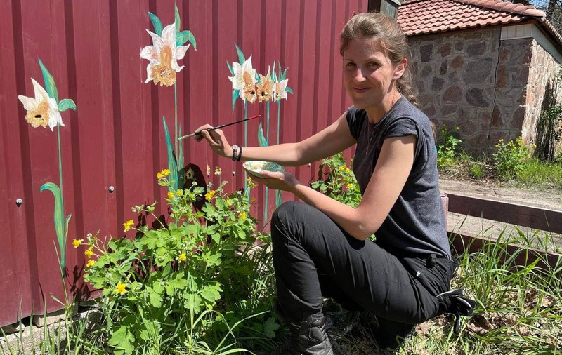 Artă din gloanțe. Un artist plastic desenează flori peste urmele lăsate de cartușe în gardurile din Bucha