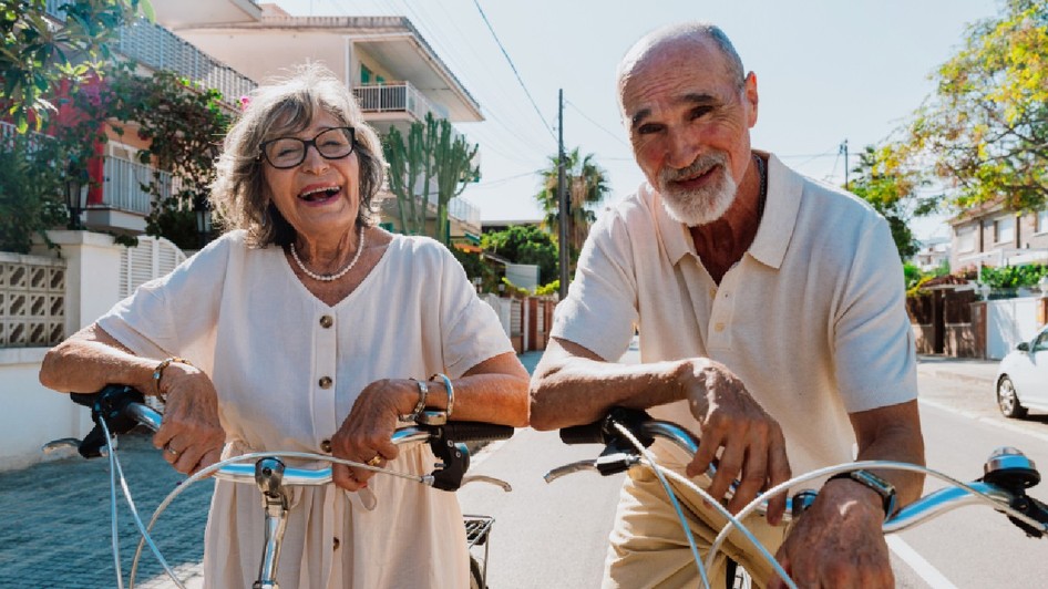 Cuplu senior fericit plimbându-se cu bicicleta în aer liber, zâmbind