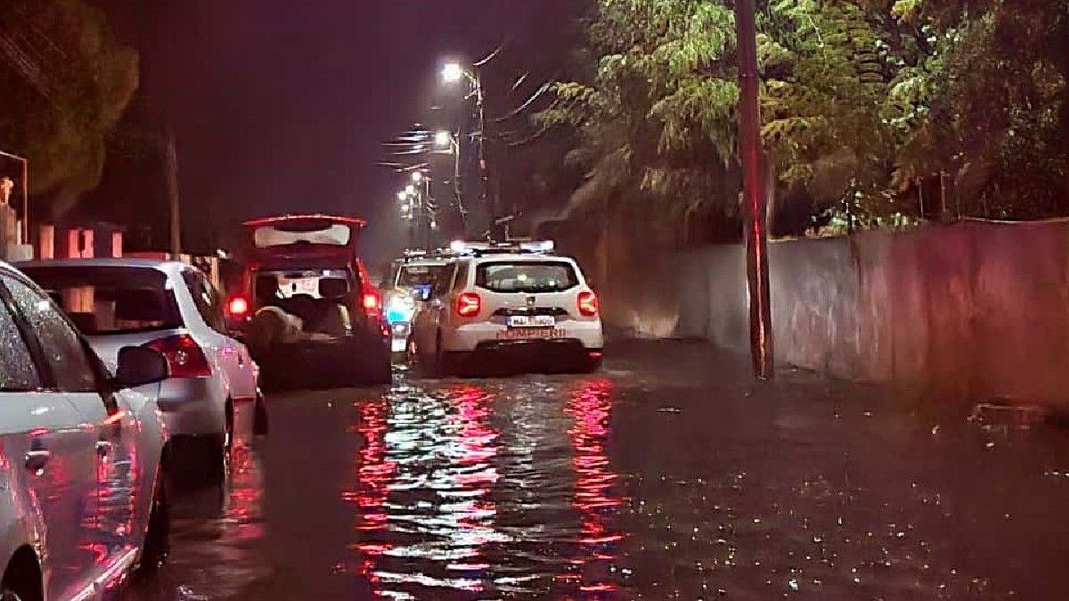 Mai multe mașini pe o stradă inundată, noaptea
