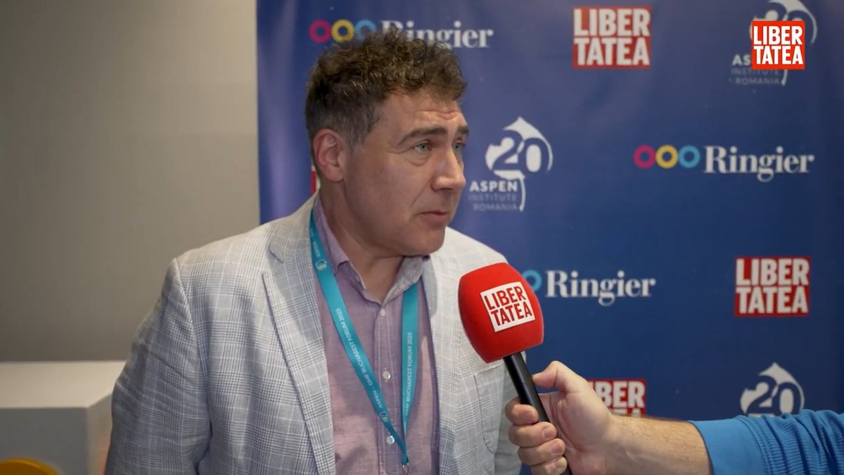 Cosmin Vladimirescu, General Manager România și Croatia al Mastercard in sacou și camasa de culoare deschisa, cu un badge cu snur albastru la gat, vorbeste la microfonul cu sigla Libertatea