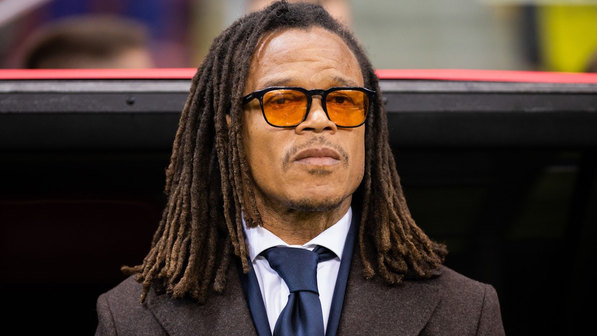 Imagine cu Edgar Davids. Poartă o jachetă închisă la culoare, o cămașă albă și o cravată albastru închis