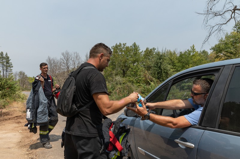 Voluntarii greci le aduc provizii pompierilor