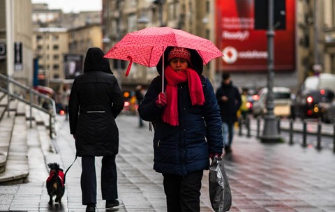Femeie cu umbrelă plimbându-se într-o zi ploioasă pe bulevardul principal al orașului București, România