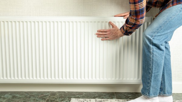Persoana inspectează radiatorul pentru a se asigura că căldura este gata pentru sezonul de încălzire