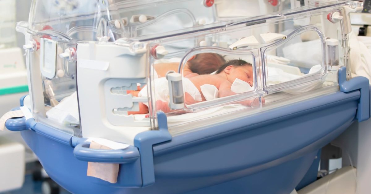 Doi bebelusi nou-născuți stau e burtică într0un incubator albastru in spital
