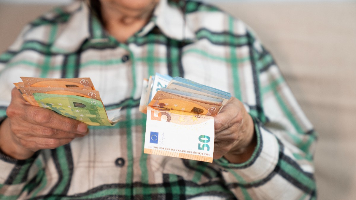 O femeie care stă jos și ține în mână bancnote de euro