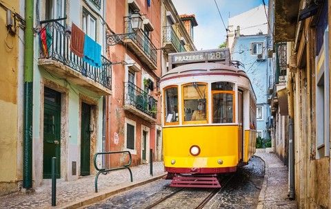 Celebrul tramvai galben de epocă nr 28 pe străzile înguste ale cartierului Alfama din Lisabona, Portugalia 