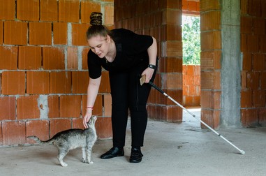 Ali o mângâie pe Insistenta, una din cele zece pisici pe care le are, în timpul unei plimbări în viitoarea casă a bunicilor ei | Foto Oana Brîndușe