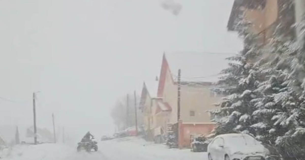 Prima ninsoare la Rânca, un tânăr pe ATV se plimbă pe drumul acoperit de omăt, se vede cum brazii și casele sunt acoperite de un strat de zăpadă