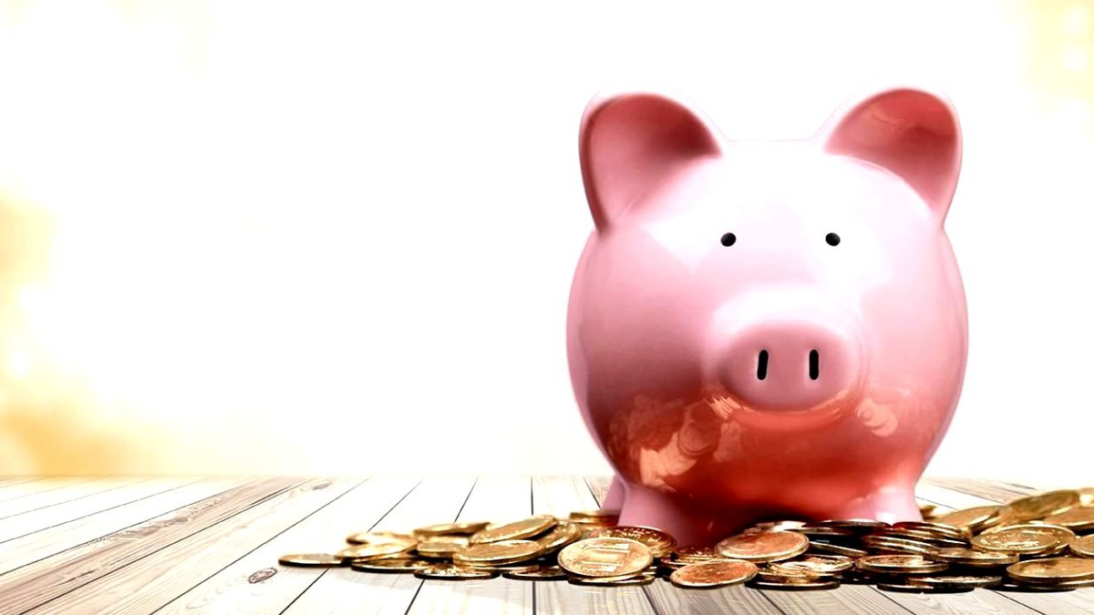 Coronavirusul atacă și pensiile. Valoarea conturilor de la Pilonul II a scăzut cu mai bine de 10% de la declanșarea pandemiei. Pușculiță în formă de porc roz și monede așezate pe lângă ea