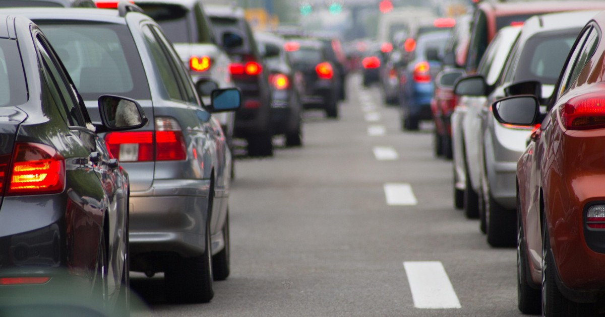 Trafic rutier aglomerat pe o șosea cu mai multe benzi, fiind surprinse din spate numeroase autoturisme oprite sau circulând în coloană, cu stopurile aprinse.