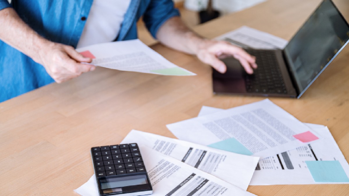 Un bărbat verifică și calculează cheltuielile generate de facturi la gaze, curent sau apă